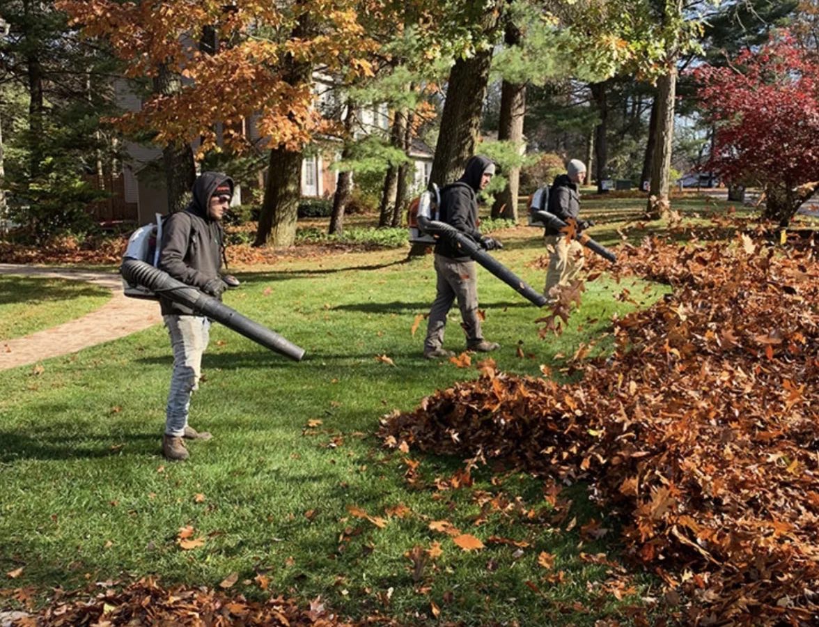 Three crew members clearing fall leaves with backpack blowers